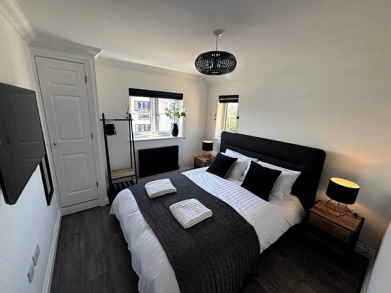 Een slaapkamer met een groot bed, twee nachtkastjes, een raam en een deur.