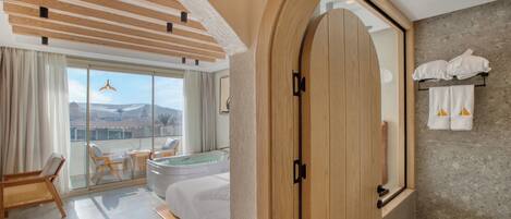 Habitación de hotel moderna con balcón, una puerta grande de madera y vistas a la montaña.