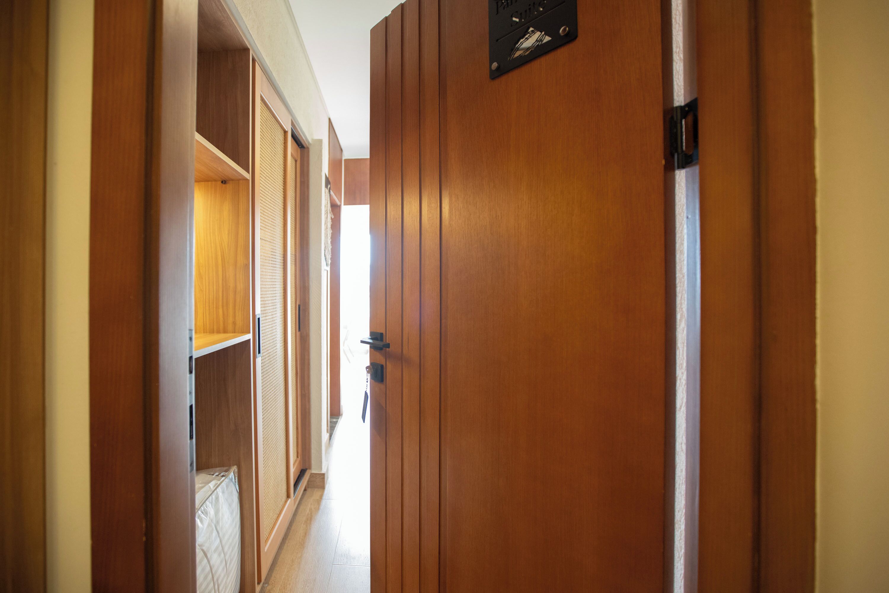 Een gang met houten deuren en een bordje met de tekst 'Pantry Suites'.