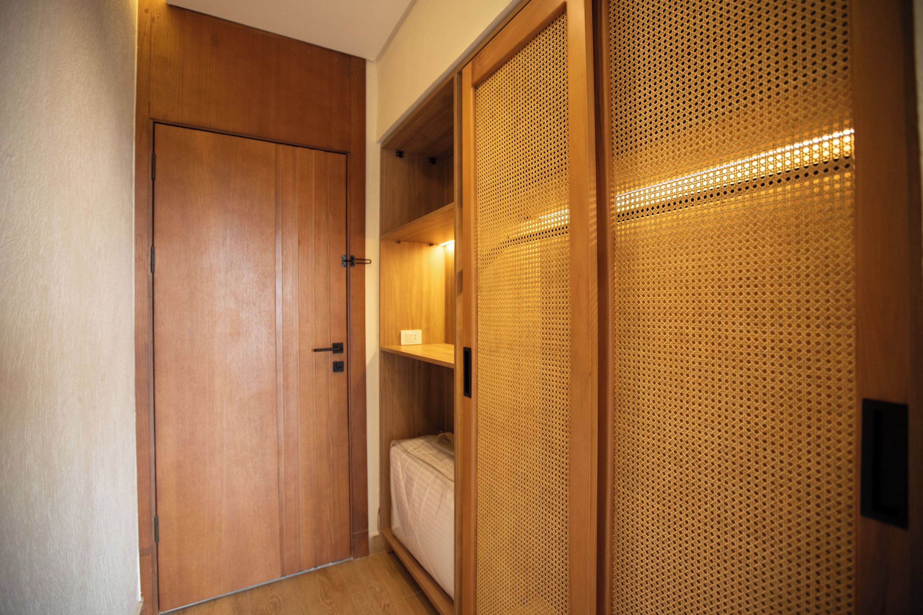 Un couloir étroit avec une armoire en bois et un paravent doté d’un motif ajouré.