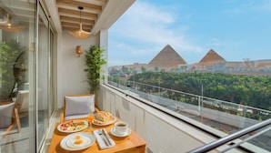 Un balcon aménagé pour le petit-déjeuner, offrant une vue sur les pyramides et la végétation environnante.