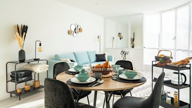 A modern dining area with a round table, black chairs, and a light blue sofa. - F4 Family apartment between Paris & Disneyland (Lognes)
