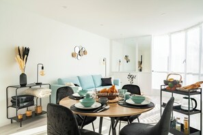 A modern dining area with a round table, black chairs, and a light blue sofa. - F4 Family apartment between Paris & Disneyland (Lognes)
