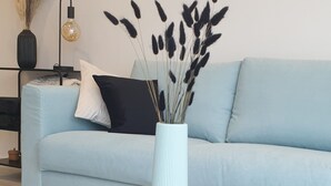 A modern living room with a light blue sofa, a round wooden coffee table, and a vase with dried plants. - F4 Family apartment between Paris & Disneyland (Lognes)