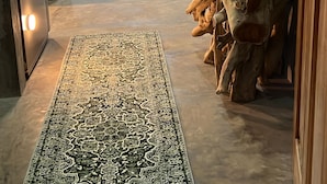 Un salon moderne avec un grand tapis, un canapé et une sculpture en bois.