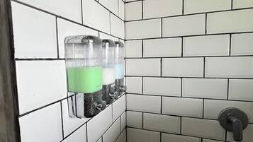 Un baño con azulejos blancos tipo metro, un secador de manos y un perchero para toallas.