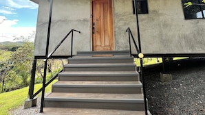 Un bâtiment doté d’une porte en bois, de murs en béton et d’un toit en métal.