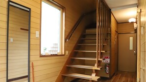 Un interior de madera con una escalera, una ventana y una puerta.