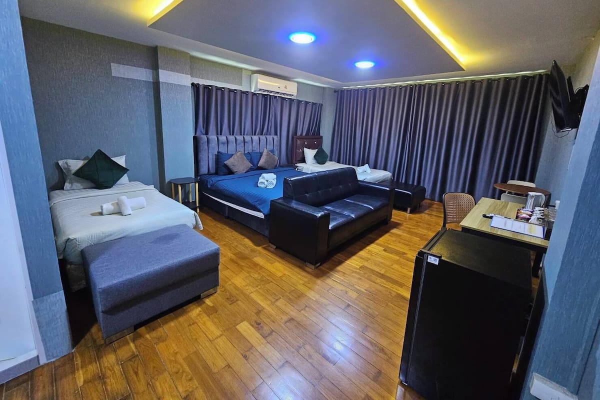 Ein Hotelzimmer mit Bett, Sofa, Schreibtisch, Fernseher und Deckenleuchte.