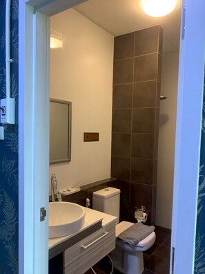 A bathroom with a white sink, mirror, and toilet, a towel rack, and a wall-mounted light fixture. - Grabsleep&Khokeng (Bangkok)