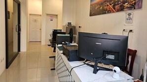 A hotel reception area with a Samsung monitor, a computer, and a desk with a keyboard and mouse. There is a sign for free WiFi and a cityscape painting on the wall. - Grabsleep&Khokeng (Bangkok)