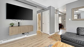 A modern living room with a flat-screen TV, wooden cabinet, and a black leather sofa. - Cozy two bedroom Breckenridge, steps away from Bus stop to mountain and downtown (Breckenridge)