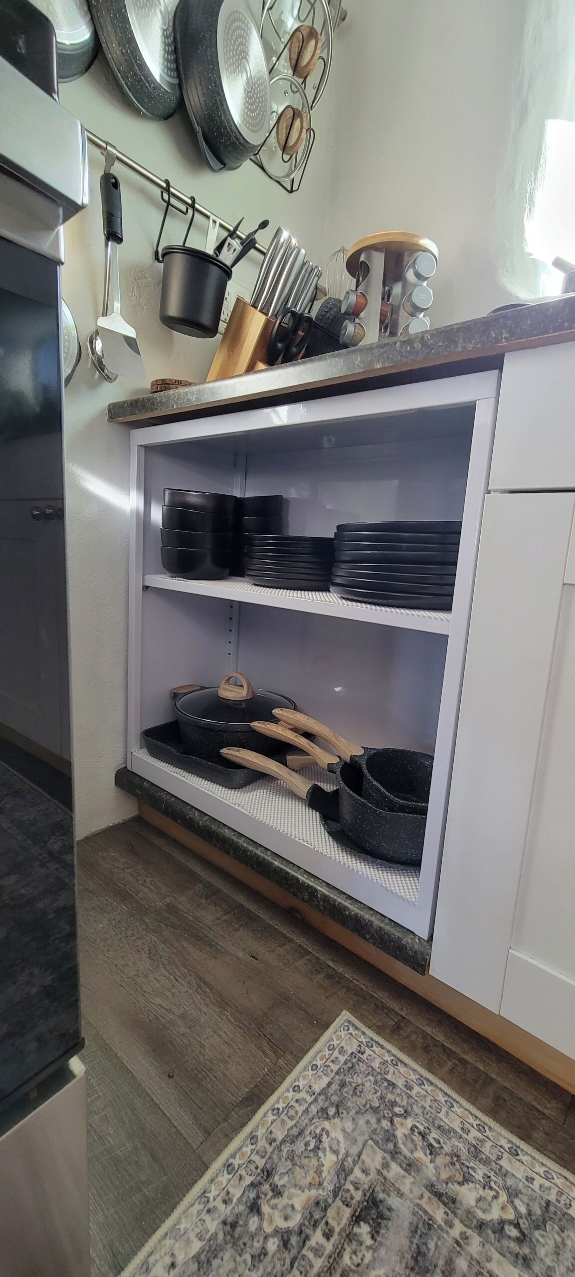 Eine Küche mit einer eingebauten Ablage, die schwarzes Kochgeschirr, ein Holzschneidebrett und einen Topf auf der Arbeitsfläche beherbergt.