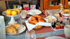 Una mesa de comedor servida con platos de comida, incluyendo croissants y frutas, y diferentes condimentos.