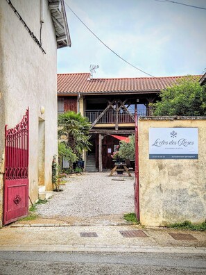 A rustic building with a red-tiled roof, a wooden staircase leading to a balcony, and a sign reading "Le clos des Roses." - le clos des roses (Perouges)