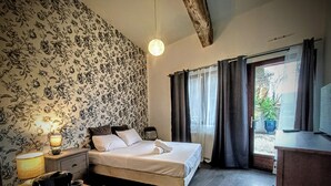 Un dormitorio con cama, mesita de noche, lámpara y cortinas.