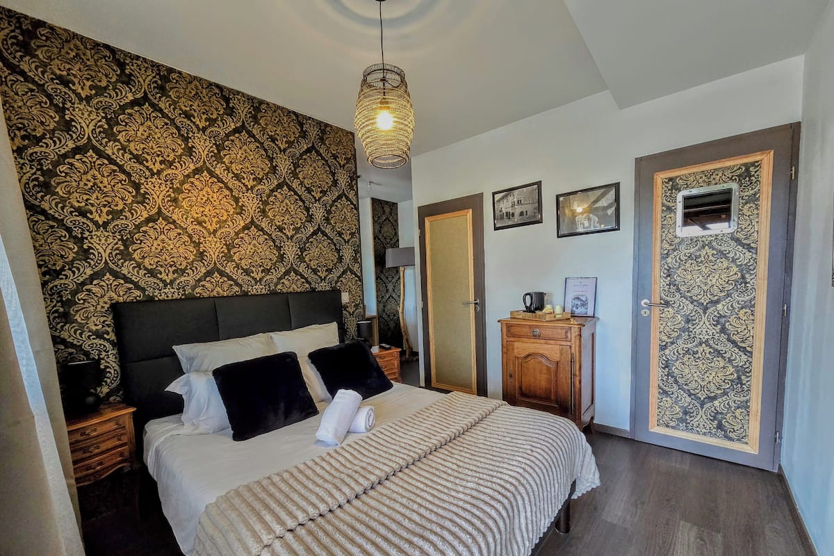 A bedroom with a large bed, a nightstand, a dresser, and a wardrobe.