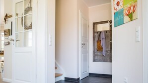 A hallway with a dark tiled floor, white walls, and a door with a glass panel. - Ferienhaus Schilfrohrsanger, Fuhlendorf (Fuhlendorf)