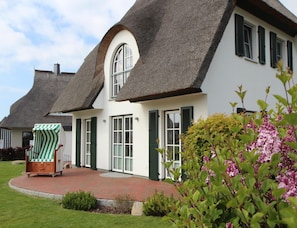 A traditional house with a thatched roof, white walls, and green shutters. - Ferienhaus Schilfrohrsanger, Fuhlendorf (Fuhlendorf)