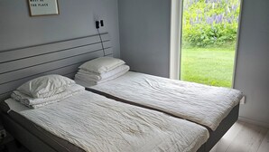 A bedroom with two single beds, a grey wardrobe, and a window with a view of greenery. - Skidvägen 4a - Lodge (Jarvso)