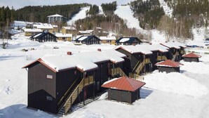 A snow-covered resort with multiple cabins and a ski lift in the background. - Skidvägen 4a - Lodge (Jarvso)