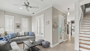 A spacious living room with a gray sofa, a coffee table, and a staircase leading to another level.