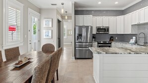 A modern kitchen with white cabinets, stainless steel appliances, and a marble countertop.