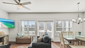 A spacious living room with a large sofa, a dining table, and a ceiling fan. - Golf Cart, Great Location, Close to Beach Access (Santa Rosa Beach)