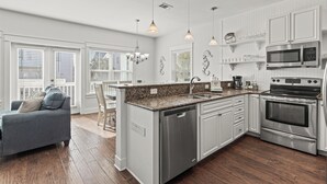 A modern kitchen with white cabinetry, stainless steel appliances, and a granite countertop. - Golf Cart, Great Location, Close to Beach Access (Santa Rosa Beach)