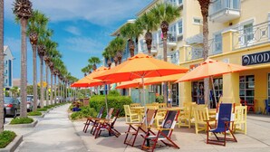 A beachfront hotel with outdoor seating, palm trees, and a clear sky. - Golf Cart, Great Location, Close to Beach Access (Santa Rosa Beach)