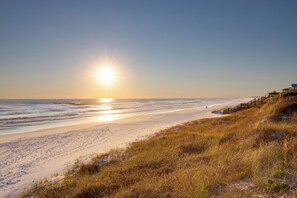 Een strand met een houten looppad dat naar een gebouw leidt.