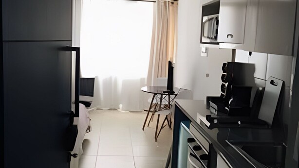 A compact kitchen with a dining area, a microwave, and a small table. - Estudio Urbano en Santiago (Santiago)