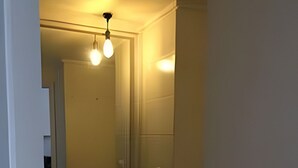 A small, narrow bathroom with a white sink, a mirror, and a light fixture above the mirror. - Estudio Urbano en Santiago (Santiago)