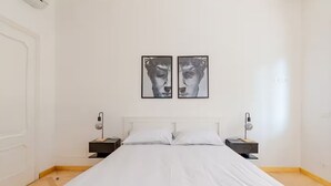 A bedroom with a large bed, white walls, and two bedside tables with lamps. - Luxury apartment " Magdalene House " (Roma)