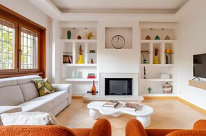 A modern living room with a fireplace, white sofas, and a coffee table.