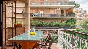 A balcony with a table and chairs, a view of a multi-story building, and a metal railing. - Luxury apartment " Magdalene House " (Roma)