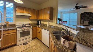 A kitchen with granite countertops, wooden cabinets, a stove, a dishwasher, and a ceiling fan. - ★Full Equipped Villa 8 guests 2Br/2Bth Pool and Free Shuttle to Disney Parks★ (Kissimmee)