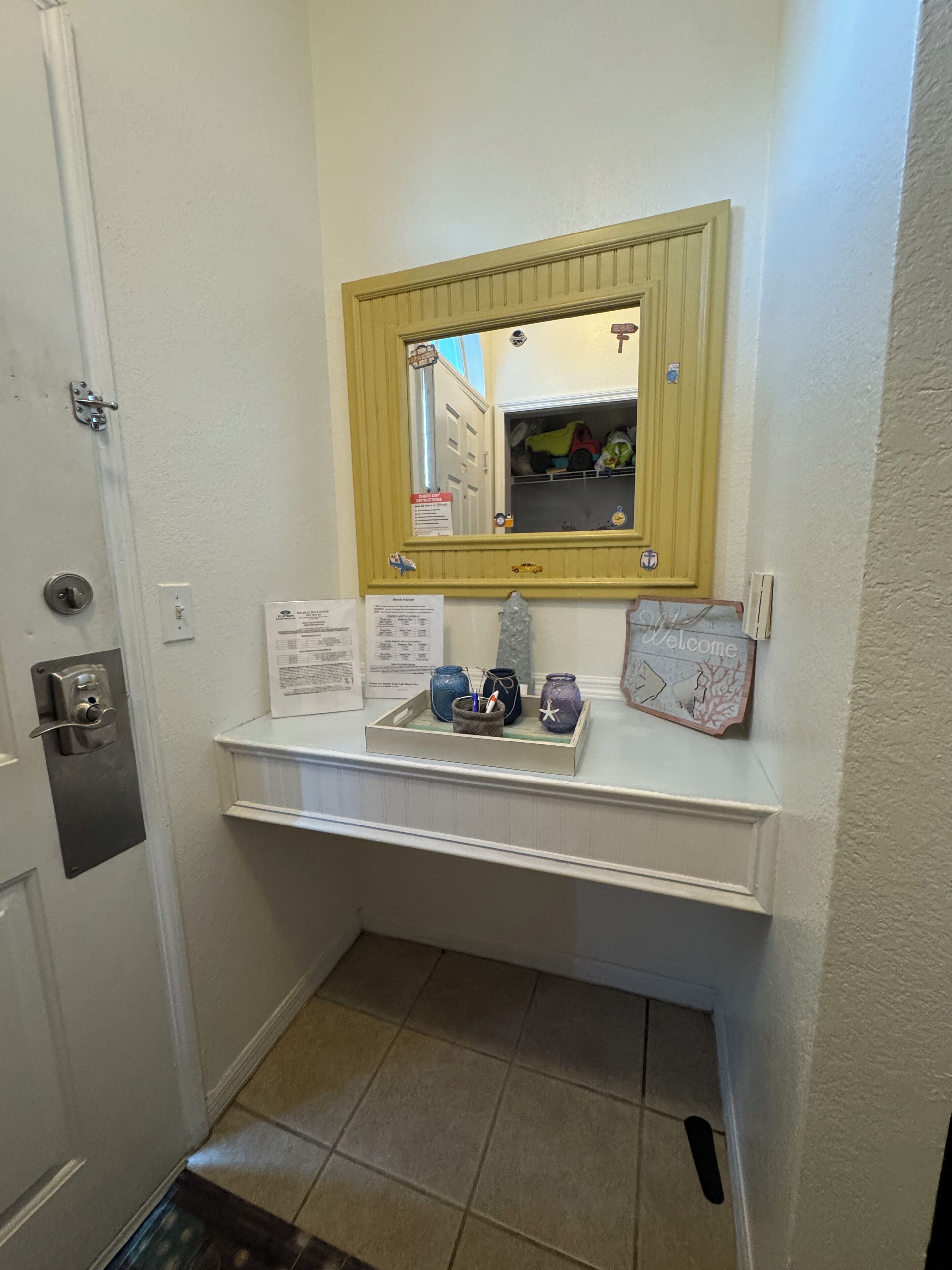 Une salle de bain avec un meuble-lavabo blanc, un miroir avec un cadre en bois et une petite étagère ornée d’objets décoratifs.