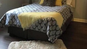 Een slaapkamer met een bed, nachtkastje, lamp en plafondventilator.