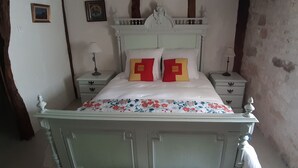 A bed with floral bedding, two nightstands with lamps, and a decorative headboard.