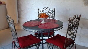 A dining area with a round table, two chairs, and a decorative light fixture.