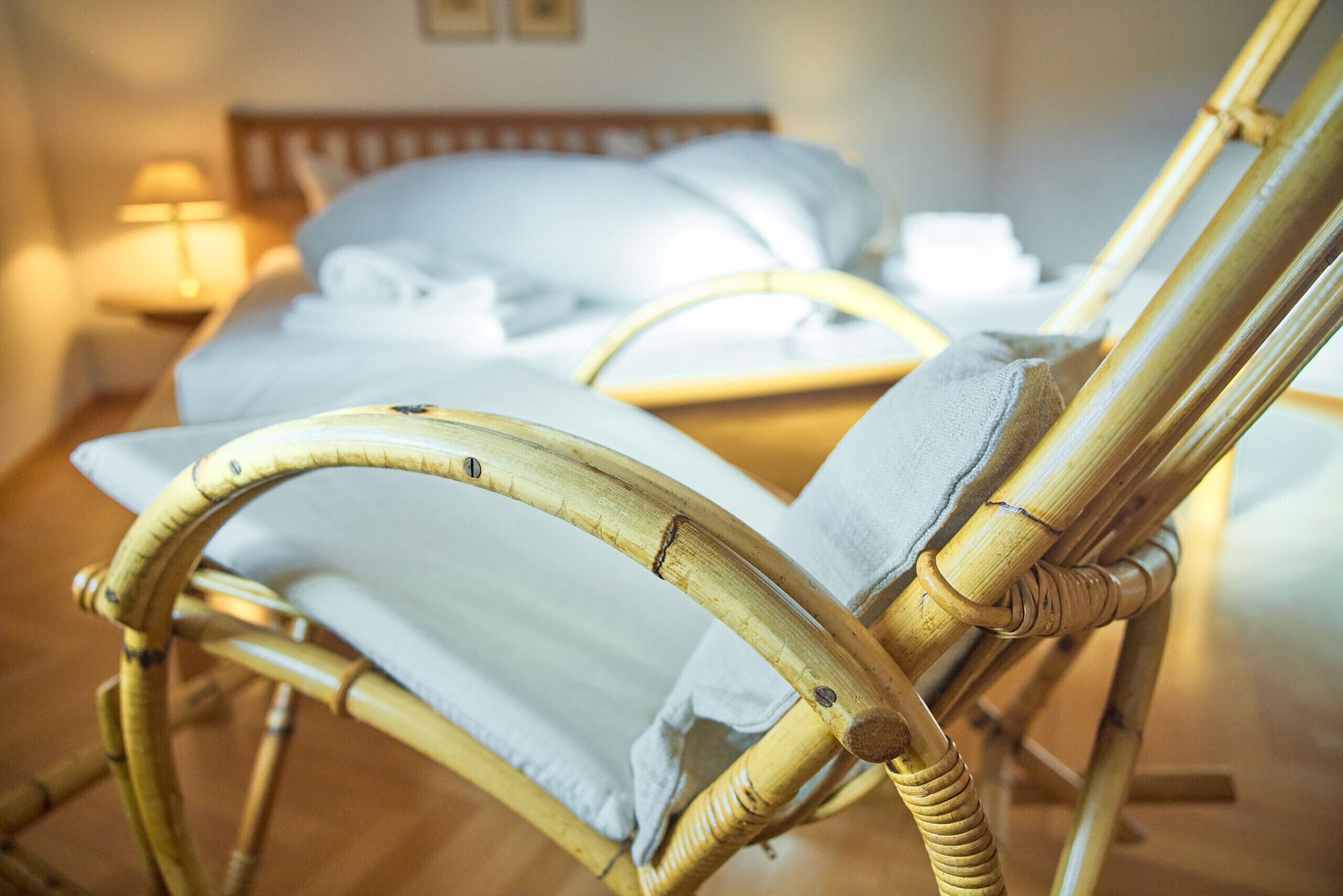 A wicker chair with a white cushion in a hotel room.
