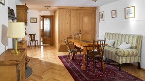 Una habitación con una mesa de madera, sillas, un sofá y una lámpara.