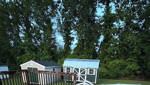 Une piscine avec une terrasse en bois et un petit abri de jardin.