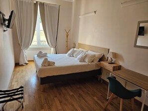 A hotel room with a bed, a desk, a chair, and a window with curtains. - Ÿou'RHome Suite - Your suite in the heart of Rome. On vacation, just like at home   (Roma)