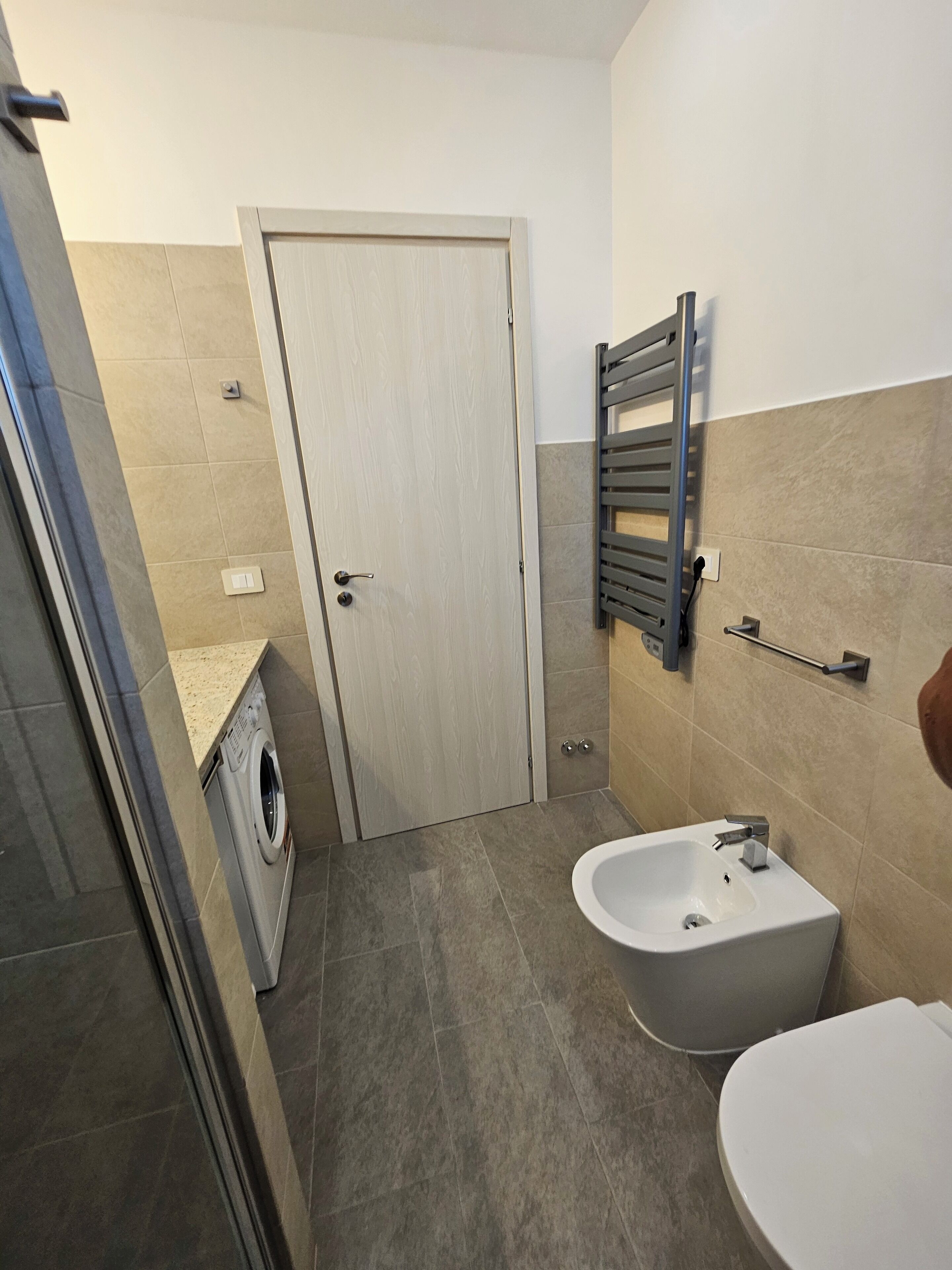 Une salle de bain équipée d’un lave-linge, d’un bidet et de toilettes.