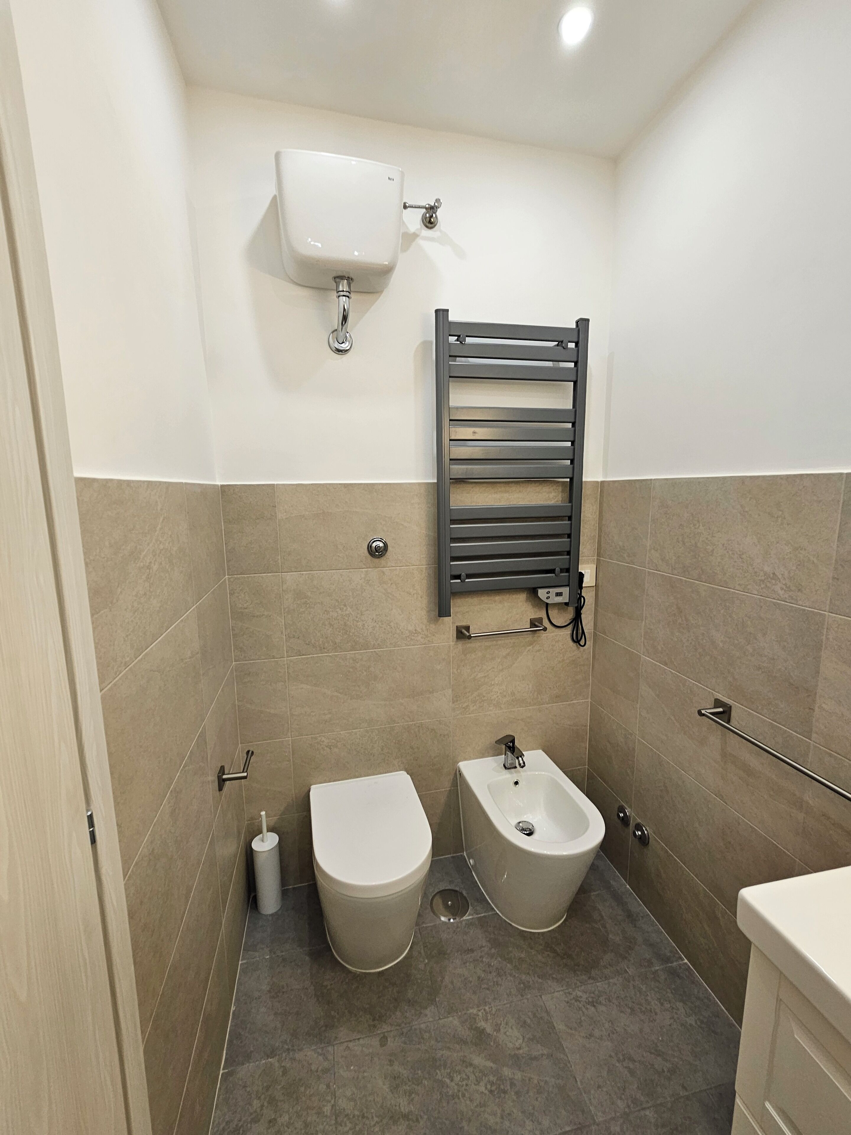 Une salle de bain moderne équipée de toilettes, d’un bidet et d’un porte-serviettes.
