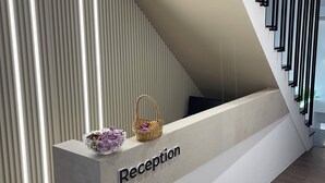 Una recepción de diseño moderno, una escalera con barandillas negras y un piso de madera.