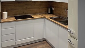 Una cocina moderna con armarios blancos, un protector contra salpicaduras de madera, electrodomésticos de acero inoxidable e iluminación empotrada.