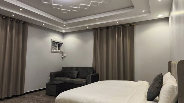 A modern hotel room with a large bed, a sofa, and a small table. - Al Rayhan Suites (Madinah)